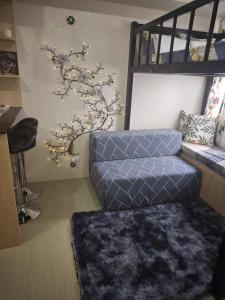 a living room with a blue couch and a tree at The Comfort Pad in Cagayan de Oro