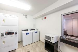 una pequeña cocina con electrodomésticos blancos y TV. en Motel 6-Klamath Falls, OR en Klamath Falls