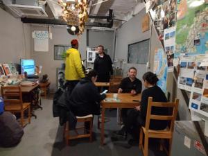 a group of people sitting at a table in a room at TONARINO Hostel for Backpackers in Kobe