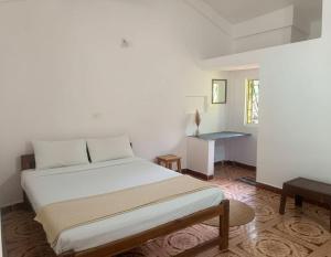 a white bedroom with a bed and a desk at Rudresh Guest House in Arambol +14 photos