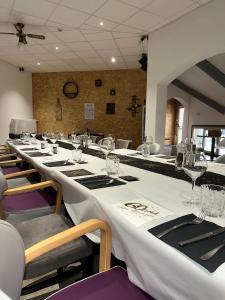 een lange eetkamer met een lange tafel met wijnglazen bij Logis Hôtel Volcan Sancy in Nébouzat