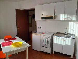 a kitchen with white cabinets and a table and a stove at A' Porta i Frustere in Rotonda