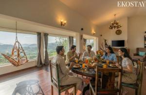 eine Gruppe von Personen, die um einen Esstisch herum sitzen in der Unterkunft EKOSTAY - Skyfall Cloud 9 Villa in Udagamandalam