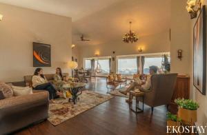 eine Gruppe von Menschen sitzt in einem Wohnzimmer in der Unterkunft EKOSTAY - Skyfall Cloud 9 Villa in Udagamandalam