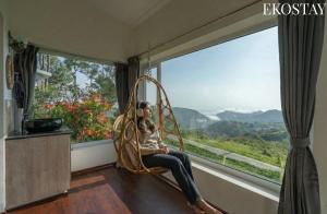 Ein Mann sitzt auf einer Schaukel vor einem Fenster in der Unterkunft EKOSTAY - Skyfall Cloud 9 Villa in Udagamandalam + 23 Fotos