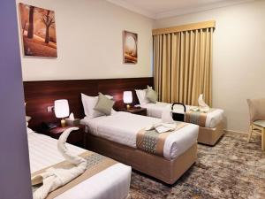 una stanza d'albergo con due letti e una sedia di فندق الريادة جراند a La Mecca