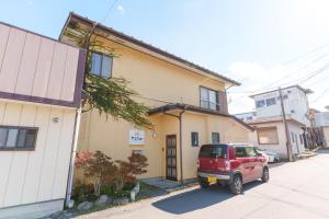 een rode auto geparkeerd voor een huis bij 富士吉田たまきや in Fujiyoshida