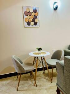 a table and chairs in a room with a painting at Lucia Homes & Stays in Dodoma