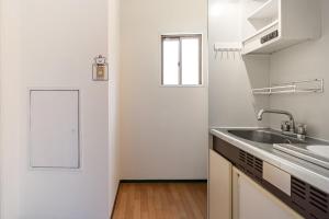 a white kitchen with a sink and a window at Peace 平和屋 in Osaka