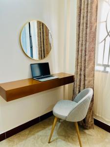 a mirror and a laptop on a desk with a chair at Lucia Homes & Stays in Dodoma