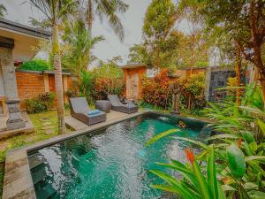 een zwembad met twee stoelen en een huis bij Ubud Suarga Private Pool Villa in Ubud