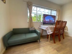 een woonkamer met een groene bank en een tafel bij Albany house in Motungarara