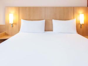 - un grand lit blanc avec deux oreillers dans l'établissement Ibis Madrid Calle Alcalá, à Madrid