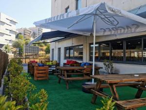 a patio with wooden benches and an umbrella at Hotel ibis Leiria Fatima in Leiria