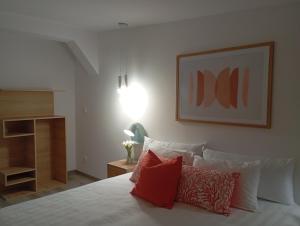 ein Schlafzimmer mit einem weißen Bett mit roten Kissen in der Unterkunft L'Etage 1 2 in Pointe-à-Pitre