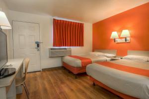 a hotel room with two beds with orange walls at Motel 6-Chino, CA - Los Angeles Area in Chino