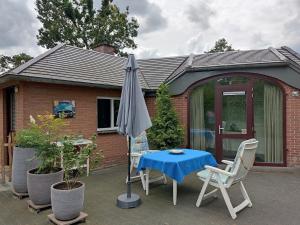 a patio with an umbrella and a table and chairs at Gastenverblijf Op den dreef in Hamont