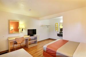 a hotel room with a bed and a desk with a television at Travelodge by Wyndham Brattleboro VT in Brattleboro +29 photos