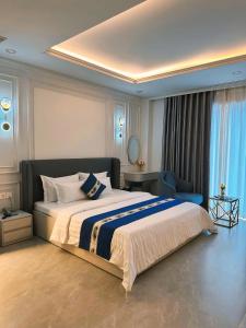 een slaapkamer met een groot bed en een blauwe stoel bij Eden Hotel in Ho Chi Minh-stad