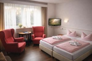 ein Hotelzimmer mit zwei Betten und zwei Stühlen in der Unterkunft Hotel zur Struth in Eschwege + 3 Fotos