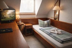 ein kleines Zimmer mit einem Bett und einem Fernseher in der Unterkunft Hotel zur Struth in Eschwege