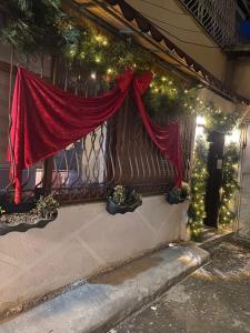 een raam met een rood gordijn en kerstverlichting bij Romeo apt with private garden in Korçë