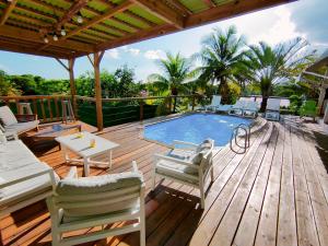 a wooden deck with a swimming pool and chairs on it at Villa Ticitron in Sainte-Anne