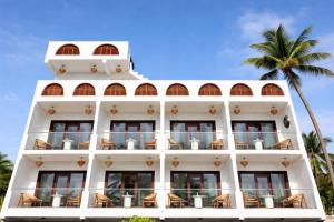 a white building with chairs and a palm tree at Palma De Maldives in Thoddoo
