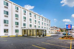 un gran edificio blanco con una parada de autobús en un aparcamiento en Motel 6-Framingham, MA - Boston West, en Framingham