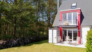 a house with a red and white deck and chairs at Deichhaus Boddentraum in Breege
