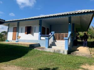 Un uomo in piedi di fronte a una casa di 2BR Local House Abode a Pai