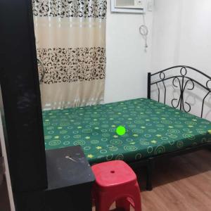 una piccola camera da letto con un letto verde con uno sgabello rosso di Staycation Condo in Manila a Manila