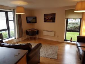 a living room with a couch and a table and windows at Baltic Quays Newcastle Upon Tyne in Newcastle upon Tyne