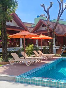 a group of chairs and umbrellas next to a pool at Tangerine Villa Patong in Patong Beach
