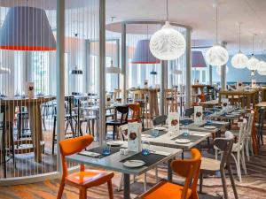 a restaurant with tables and chairs and pendant lights at Novotel Kraków City West in Kraków