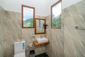 een badkamer met een wastafel en een spiegel bij Evergreen Villa - Sinharaja in Deniyaya +289 foto's