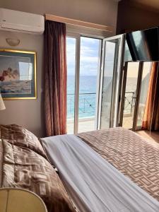 a bedroom with a bed with a view of the ocean at Queens Leriotis Hotel in Piraeus
