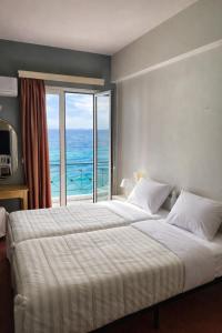 a bedroom with a large bed with a view of the ocean at Queens Leriotis Hotel in Piraeus