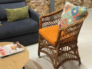 a wicker chair with an orange pillow sitting next to a table at Los tres castells in La Senia +48 photos
