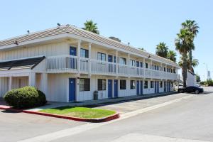 a white building with blue doors and palm trees at Motel 6-Coalinga, CA - East in Coalinga