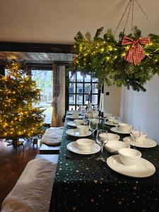 ein langer Tisch mit Tellern und Weingläsern und ein Weihnachtsbaum in der Unterkunft Fabryka Snów loft w sercu Beskidów in Istebna