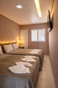 twee bedden in een hotelkamer met handdoeken erop bij LAAR Hotel in Praia Grande