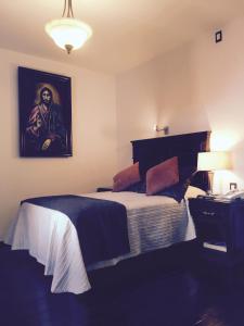 1 dormitorio con 1 cama con una pintura en la pared en Hotel San Xavier, en Querétaro