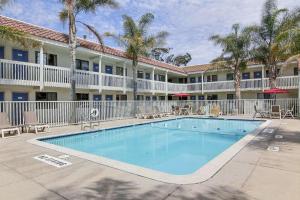 uma piscina em frente a um hotel com palmeiras em Motel 6-Lompoc, CA em Lompoc