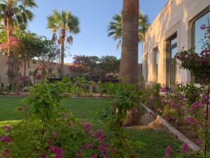 a garden with palm trees and flowers in front of a house at فيلا المنزل in Makkah