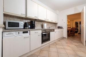 a kitchen with white cabinets and a microwave at Haus Wittow in Breege