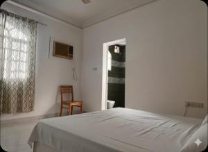 een witte slaapkamer met een bed en een raam bij Amour Hostel in Seeb