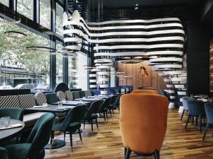 a restaurant with tables and chairs and a large chandelier at Pullman Berlin Schweizerhof in Berlin