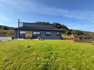 a black house on top of a green field at Luxury 3 Bedroom House - Stag Moor House in Portree