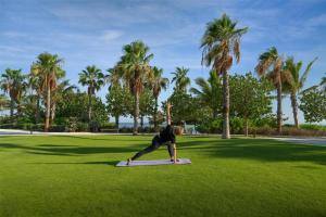 ḨanakTurtle Bay Resort - Red Sea的一名男子在棕榈树环绕的田野里做瑜伽动作。